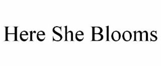 HERE SHE BLOOMS